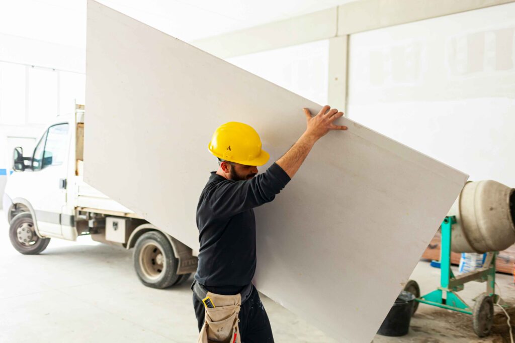 Worker installing plasterboard wall on construction site